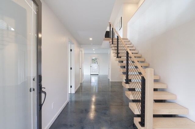 foyer entrance with baseboards, stairway, concrete flooring, and recessed lighting