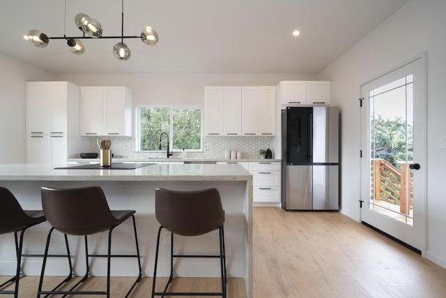 kitchen with tasteful backsplash, white cabinets, smart refrigerator, and light stone countertops