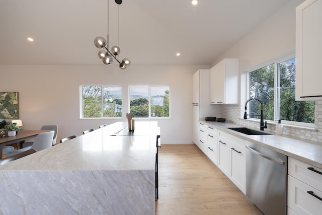 kitchen with light stone counters, a sink, white cabinets, dishwasher, and decorative light fixtures