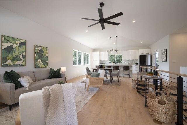 living room featuring light wood finished floors, baseboards, a ceiling fan, lofted ceiling, and recessed lighting