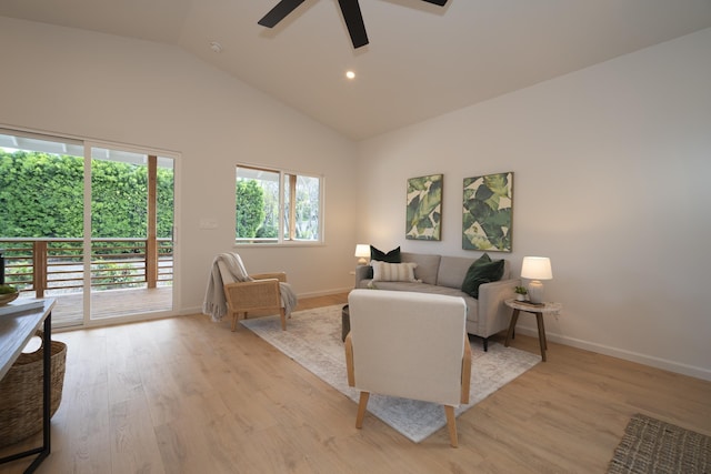 living room with high vaulted ceiling, light wood-type flooring, ceiling fan, and baseboards