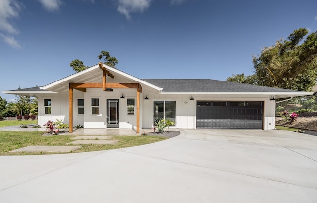 modern farmhouse featuring a garage, driveway, a shingled roof, and board and batten siding