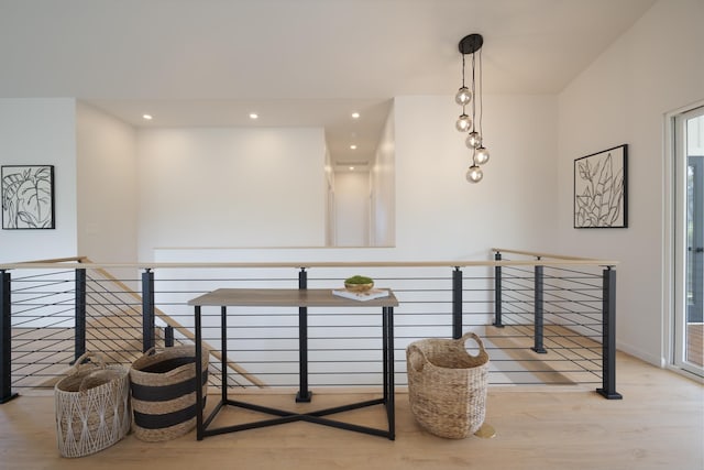 hallway with light wood-style floors, recessed lighting, and an upstairs landing