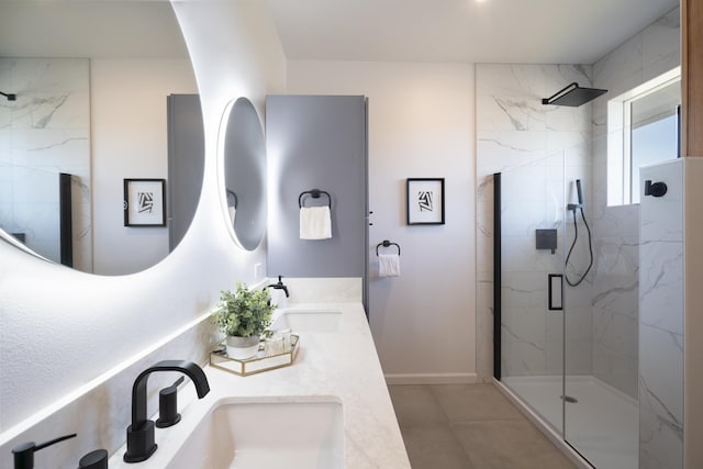 full bathroom featuring double vanity, a sink, a marble finish shower, and baseboards