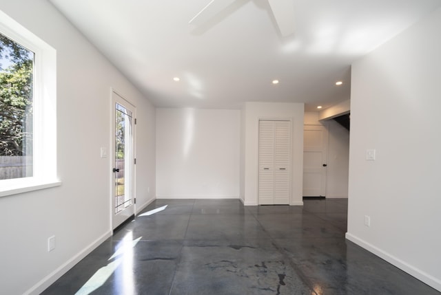 empty room featuring concrete flooring, recessed lighting, and baseboards