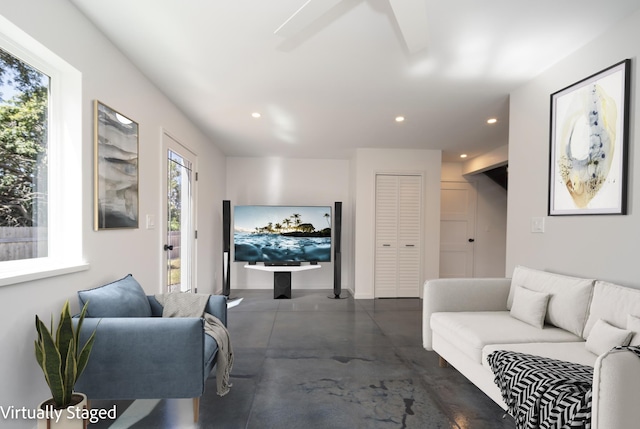 living area featuring finished concrete floors and recessed lighting