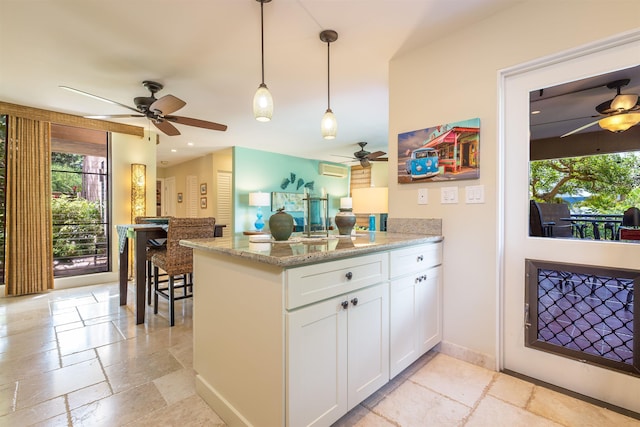 kitchen with pendant lighting, a peninsula, white cabinetry, and stone tile floors