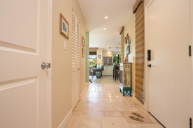 hall featuring baseboards, stone tile flooring, and recessed lighting