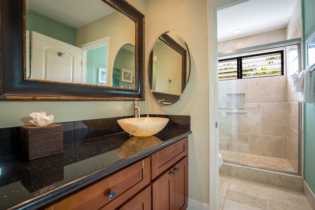 bathroom with toilet, a shower stall, vanity, and baseboards