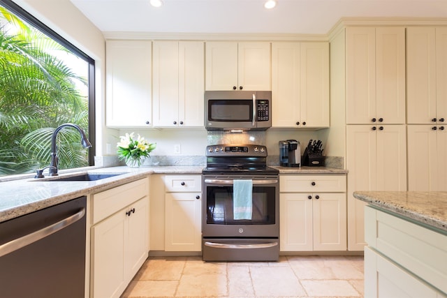 kitchen featuring appliances with stainless steel finishes, light stone counters, a sink, and recessed lighting