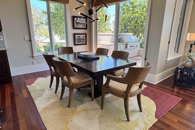 dining room featuring a wealth of natural light, baseboards, a notable chandelier, and dark wood-style flooring