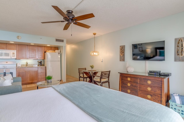 bedroom featuring a textured ceiling, light tile patterned floors, and white refrigerator