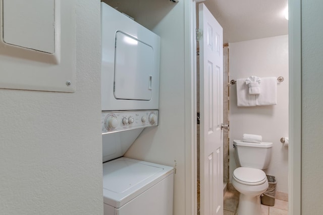 laundry room with stacked washer / drying machine, light tile patterned floors, and electric panel