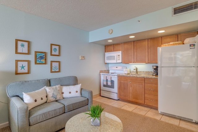 kitchen featuring a textured ceiling, light tile patterned floors, sink, and white appliances