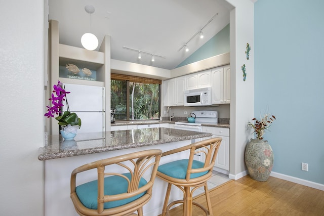 3300 Wailea Alanui Dr Unit 52D, Kihei, HI 96753 - kitchen with white appliances, a peninsula, a breakfast bar area, white cabinets, and rail lighting