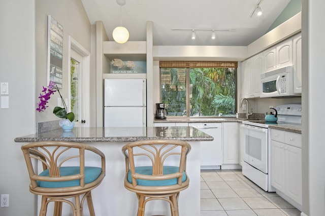 3300 Wailea Alanui Dr Unit 52D, Kihei, HI 96753 - kitchen featuring white appliances, a peninsula, white cabinets, light tile patterned flooring, and a kitchen breakfast bar