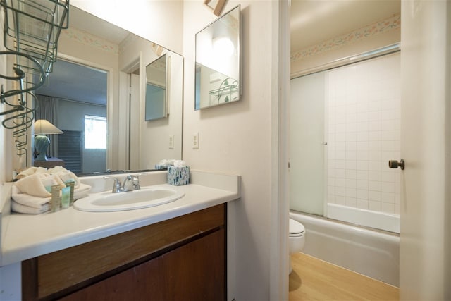 bathroom featuring enclosed tub / shower combo, toilet, vanity, and wood finished floors