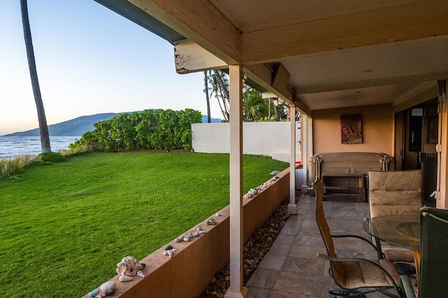 view of patio featuring a water and mountain view and a hot tub