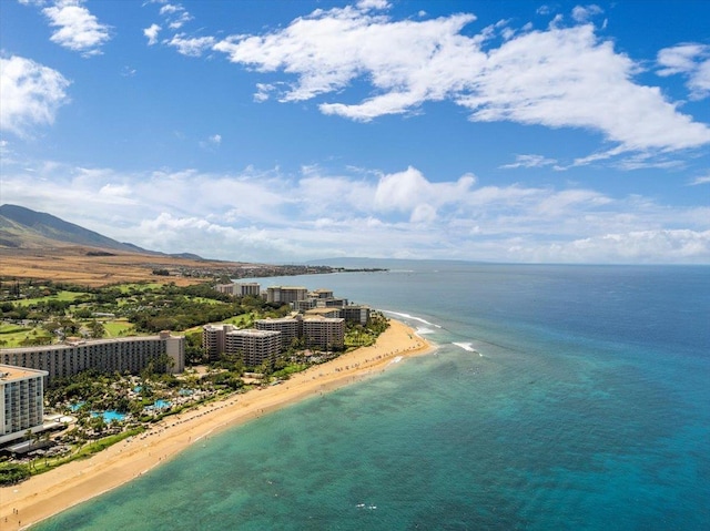 drone / aerial view with a water and mountain view and a view of the beach