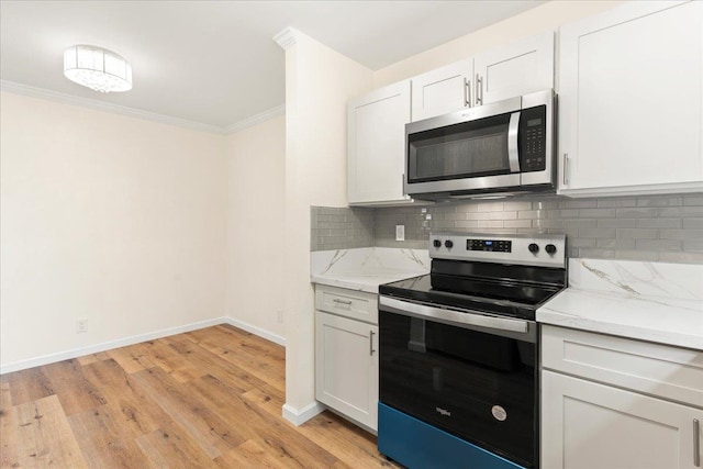 kitchen featuring light wood-type flooring, white cabinetry, appliances with stainless steel finishes, and crown molding