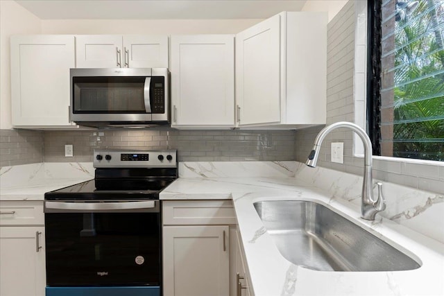 kitchen with backsplash, white cabinetry, sink, and stainless steel appliances