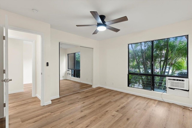 unfurnished room with cooling unit, light hardwood / wood-style floors, ceiling fan, and a wealth of natural light