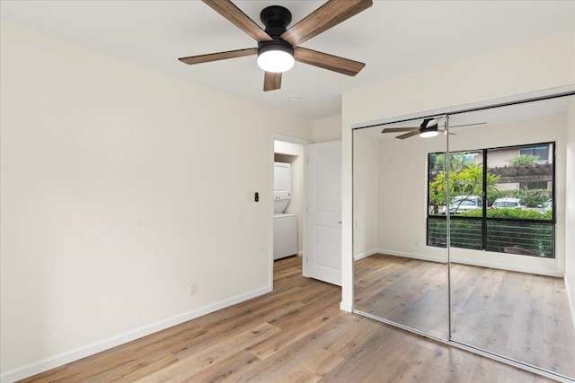 unfurnished bedroom featuring light hardwood / wood-style flooring, a closet, ceiling fan, and stacked washer / dryer