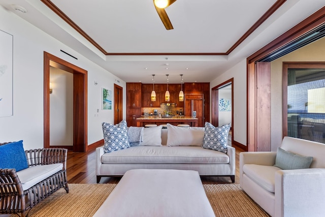 living room with wood-type flooring, ornamental molding, and ceiling fan