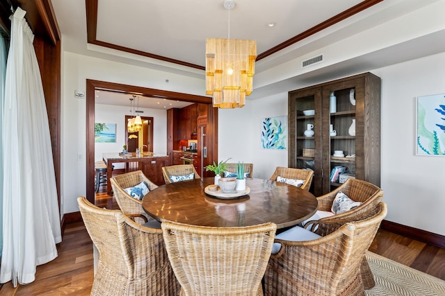 dining room with a notable chandelier, crown molding, and dark wood-type flooring