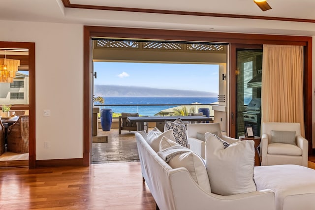 living room with a water view, ornamental molding, hardwood / wood-style floors, and ceiling fan