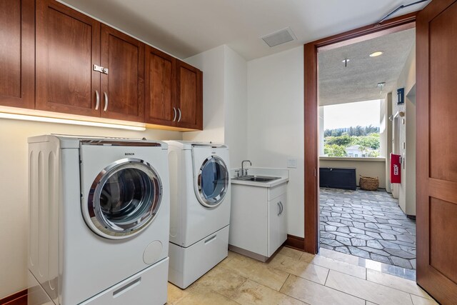 washroom with cabinets, sink, and washing machine and dryer