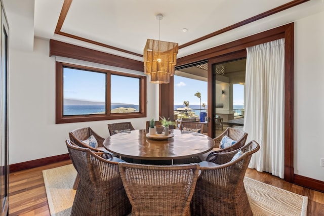 dining room with wood-type flooring, ornamental molding, and a water view