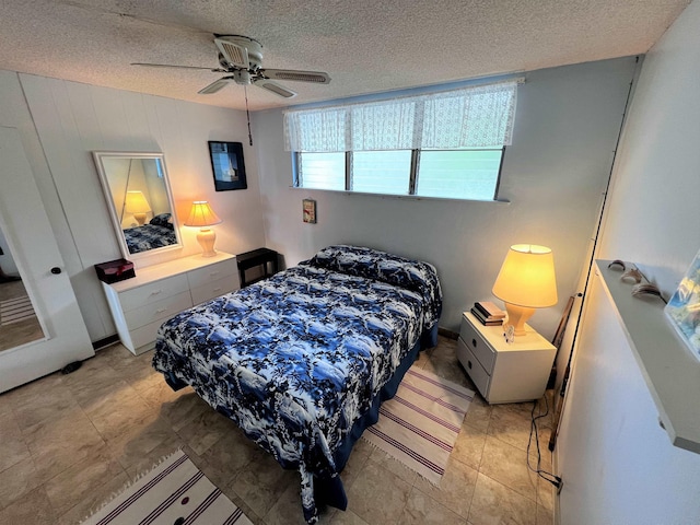 bedroom with ceiling fan and a textured ceiling