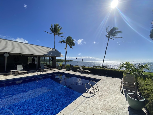 view of swimming pool with a patio area and a water view