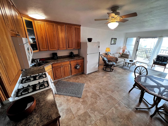 kitchen featuring white appliances, dark stone counters, sink, ceiling fan, and a textured ceiling