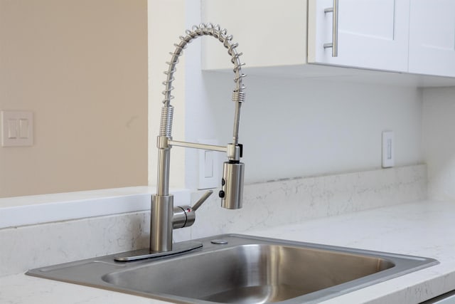 room details with light stone countertops, white cabinetry, and sink