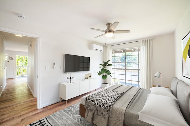 bedroom with wood-type flooring, a wall unit AC, and ceiling fan