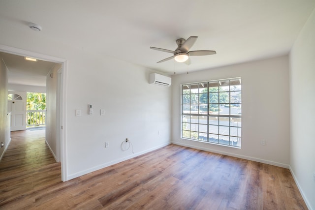 empty room featuring ceiling fan, wood-type flooring, and a wall unit AC