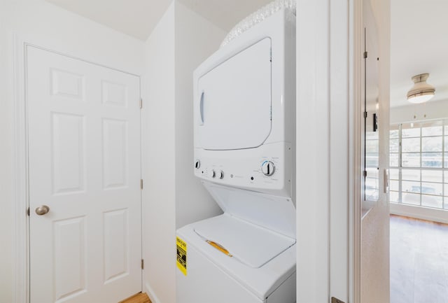 washroom with stacked washer / dryer and light wood-type flooring