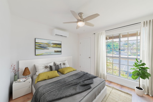 bedroom featuring ceiling fan, a wall unit AC, and light hardwood / wood-style flooring