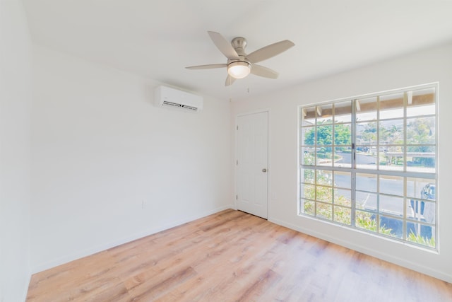 empty room featuring a wall mounted air conditioner, light hardwood / wood-style floors, and ceiling fan