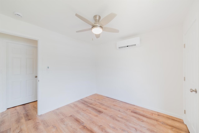 spare room with light hardwood / wood-style floors, an AC wall unit, and ceiling fan