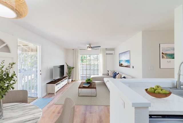 living room featuring an AC wall unit, ceiling fan, and light hardwood / wood-style flooring