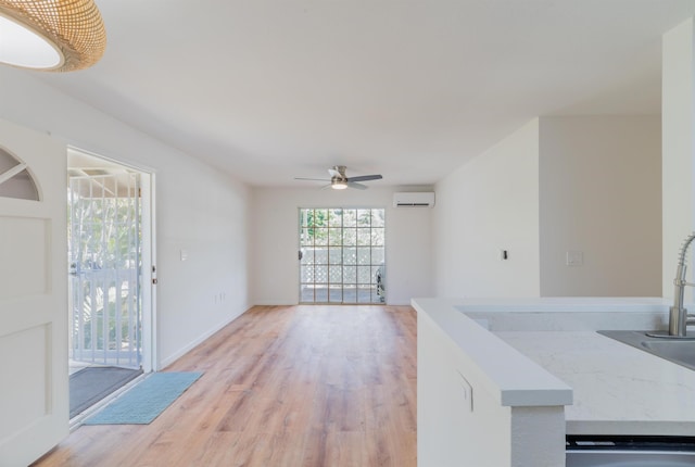 unfurnished living room featuring a wall mounted air conditioner, ceiling fan, and light wood-type flooring