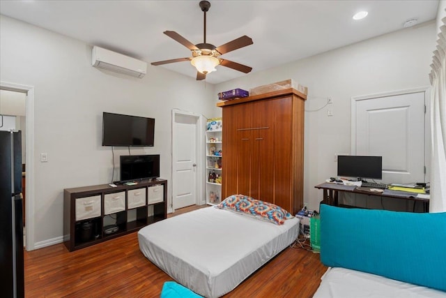 bedroom with a wall unit AC, recessed lighting, freestanding refrigerator, wood finished floors, and a ceiling fan