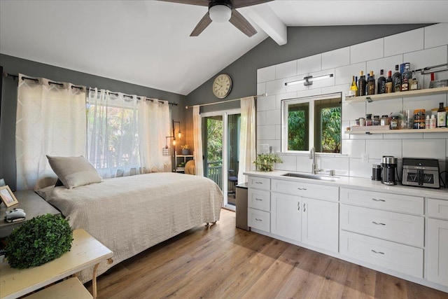 bedroom featuring access to exterior, indoor bar, lofted ceiling with beams, light wood-style floors, and a sink