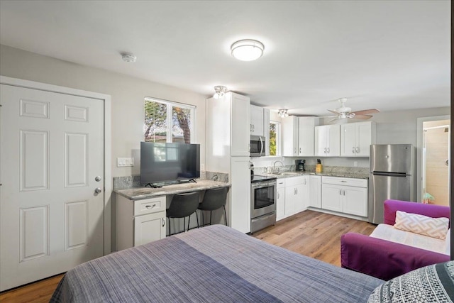 bedroom with light wood-type flooring, freestanding refrigerator, and a sink