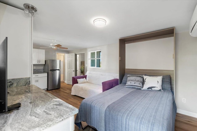 bedroom with dark wood finished floors, ceiling fan, freestanding refrigerator, and baseboards