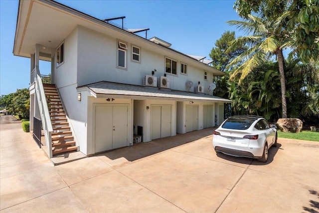 exterior space with stucco siding, stairs, concrete driveway, a garage, and ac unit