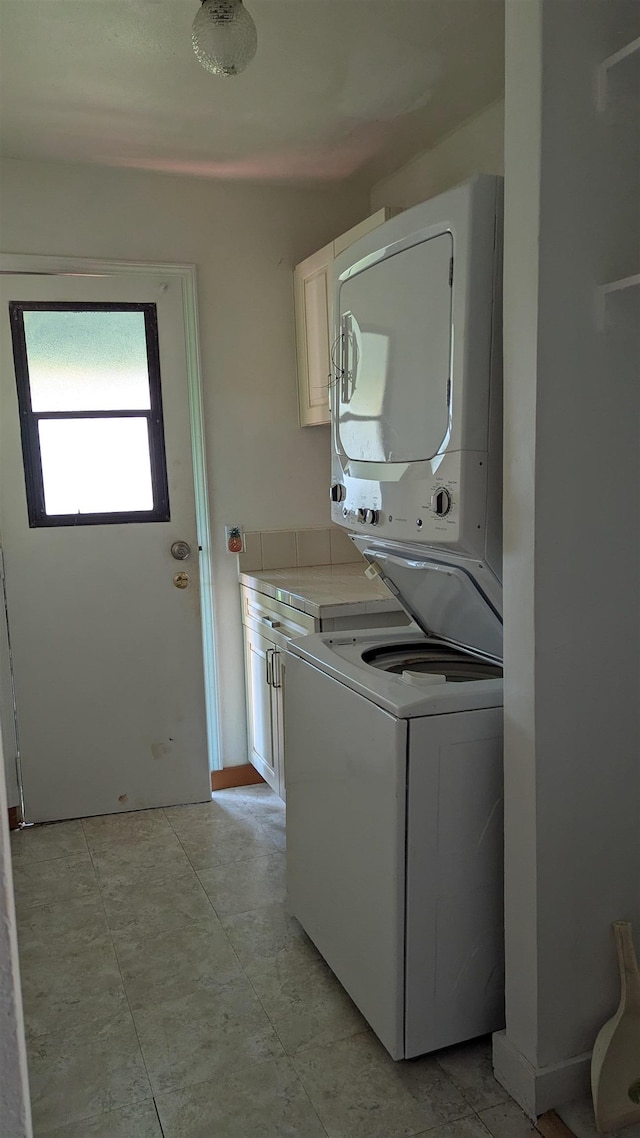 laundry room featuring stacked washer and clothes dryer and cabinet space